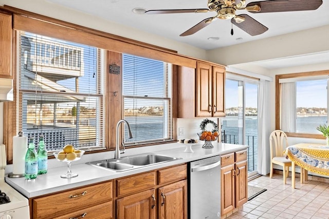 kitchen with range, dishwasher, a water view, light countertops, and a sink