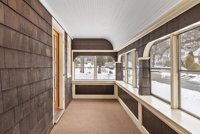 unfurnished sunroom featuring lofted ceiling, wood ceiling, and a healthy amount of sunlight