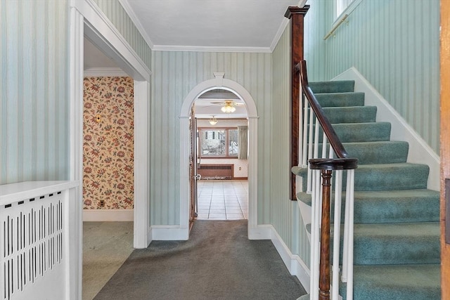 stairway featuring arched walkways, carpet floors, radiator, wallpapered walls, and crown molding