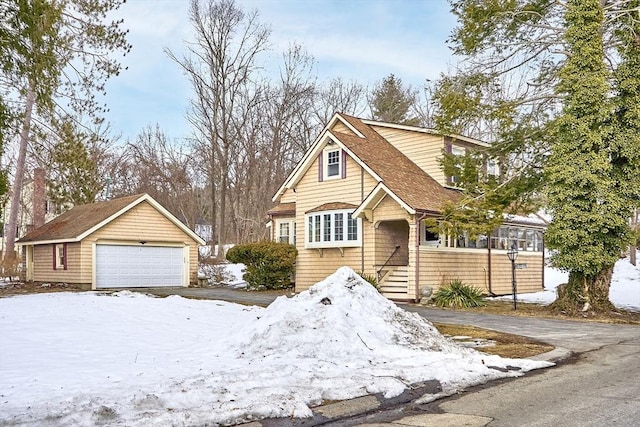 view of front of property featuring a garage, an outbuilding, and a shingled roof