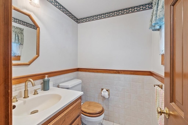 bathroom featuring tile walls, a wainscoted wall, vanity, and toilet