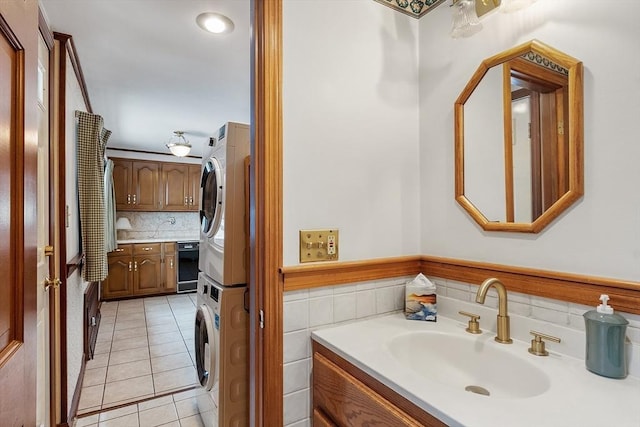 bathroom with stacked washer and dryer, tile patterned floors, tile walls, and vanity