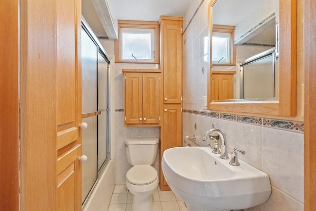 full bath featuring tile patterned flooring, a healthy amount of sunlight, tile walls, and toilet