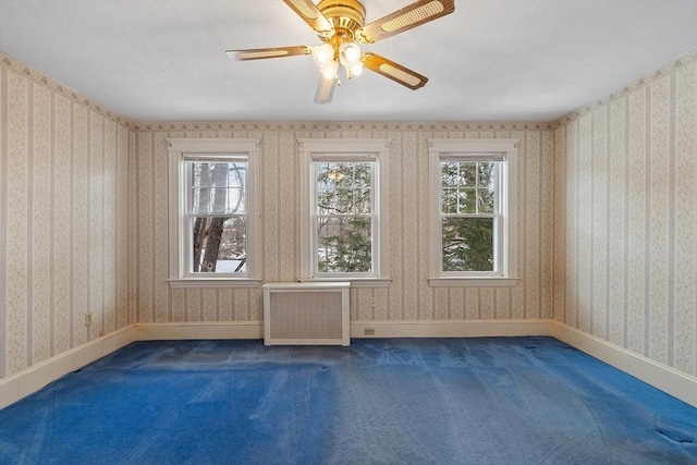 carpeted empty room with radiator, wallpapered walls, and a wealth of natural light