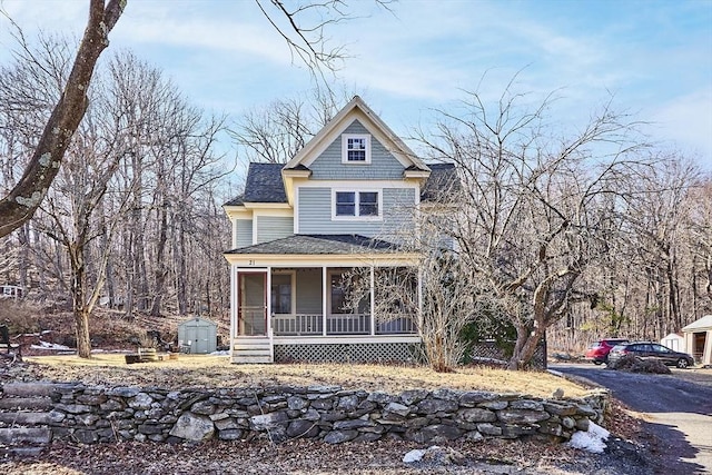 view of front facade with a sunroom and a shingled roof