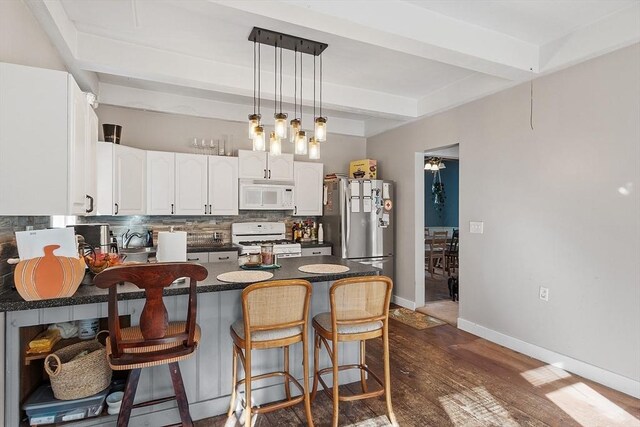 kitchen with dark countertops, backsplash, beamed ceiling, a peninsula, and white appliances