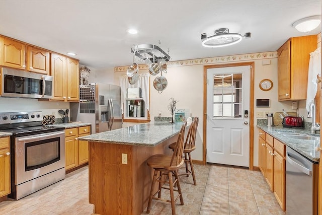 92 Hilltop Rd, Whitman, MA 02382 - kitchen featuring stainless steel appliances, a breakfast bar, a sink, stone counters, and a peninsula