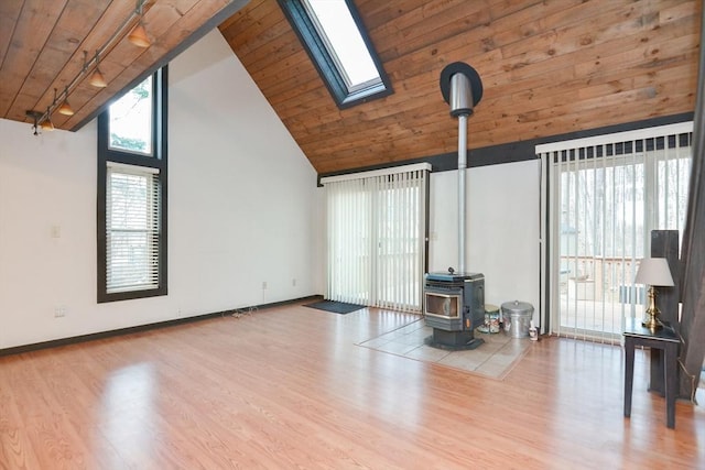 unfurnished living room with a skylight, a wood stove, a wealth of natural light, and hardwood / wood-style flooring