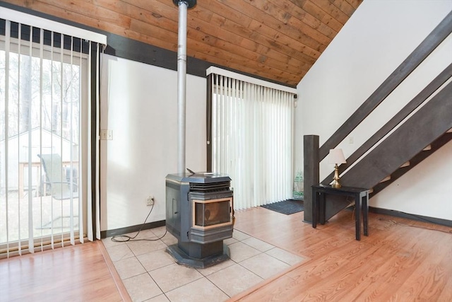 living room with vaulted ceiling, a wood stove, light hardwood / wood-style flooring, and wooden ceiling