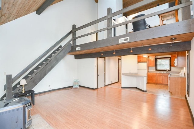 living room with light wood-type flooring, a towering ceiling, and sink