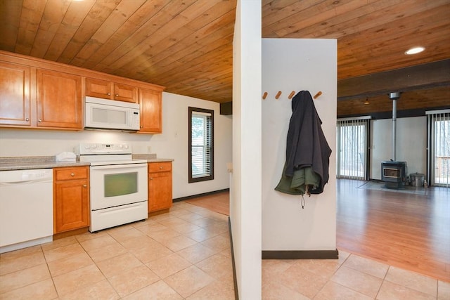 kitchen featuring wood ceiling, white appliances, light tile patterned floors, and a wood stove