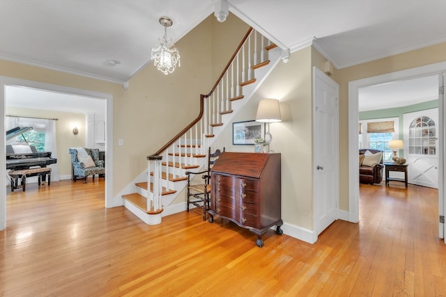 stairs with ornamental molding, hardwood / wood-style flooring, and a chandelier