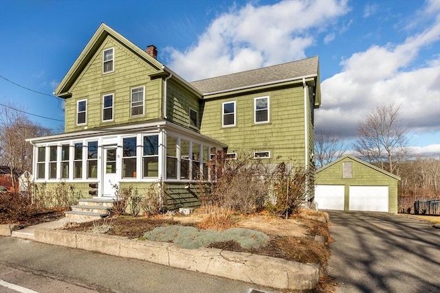 view of front property featuring a garage, an outdoor structure, and a sunroom