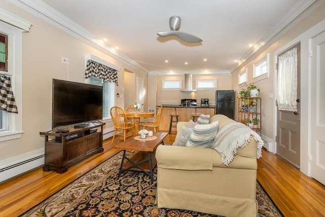 living room with baseboard heating, crown molding, and wood-type flooring