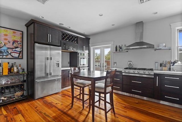 733 E 3rd St, Boston, MA 02127 - kitchen with appliances with stainless steel finishes, wall chimney range hood, open shelves, hardwood / wood-style floors, and light countertops