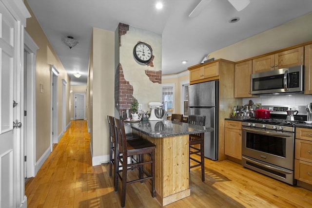 733 E 3rd St, Boston, MA 02127 - kitchen with appliances with stainless steel finishes, a breakfast bar area, light wood finished floors, decorative backsplash, and recessed lighting
