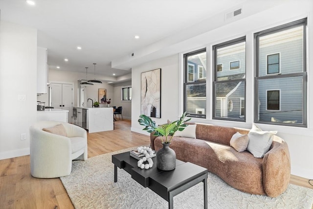 living room with baseboards, light wood-style flooring, visible vents, and recessed lighting