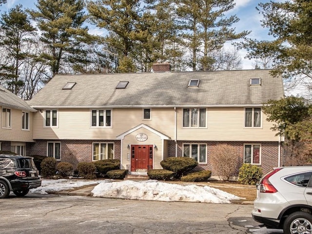 townhome / multi-family property featuring a chimney and brick siding