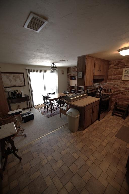 kitchen featuring brick wall, stainless steel electric range, and visible vents