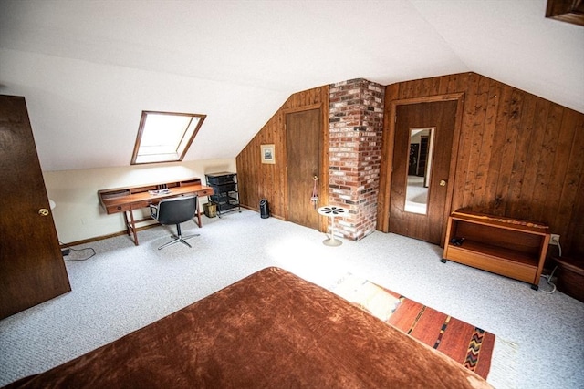 home office featuring lofted ceiling with skylight, carpet, wooden walls, and baseboards