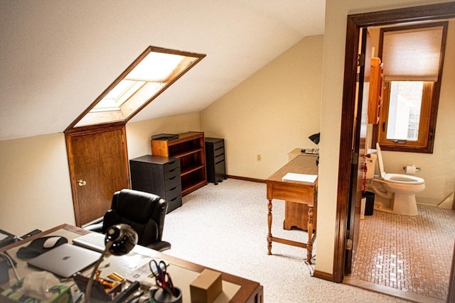 home office featuring lofted ceiling with skylight, light colored carpet, and baseboards