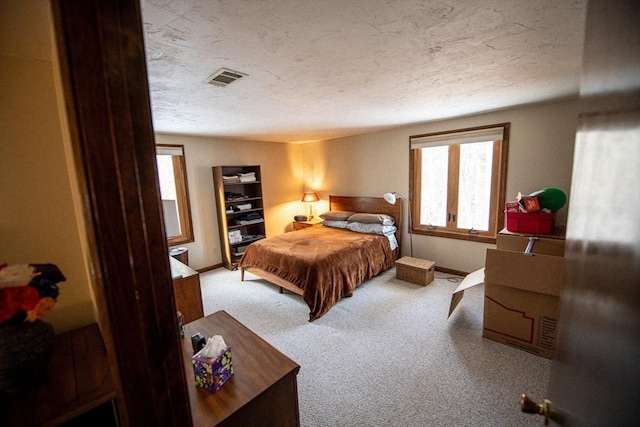 carpeted bedroom with baseboards, visible vents, and a textured ceiling