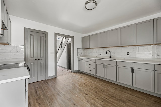 kitchen with decorative backsplash, gray cabinets, dark hardwood / wood-style flooring, and sink