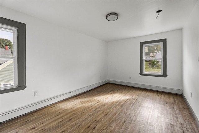 empty room featuring hardwood / wood-style floors and a baseboard heating unit