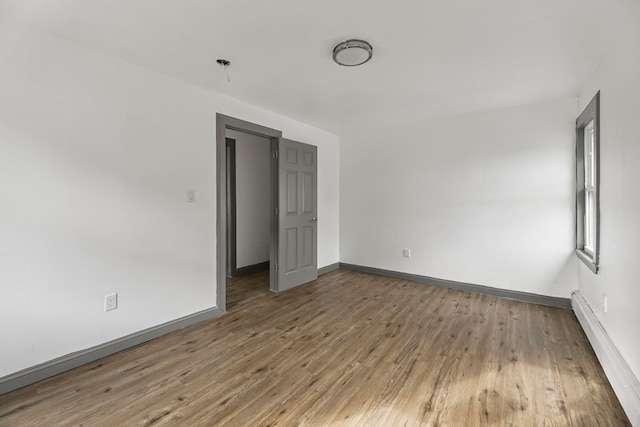 empty room with hardwood / wood-style floors and a baseboard radiator