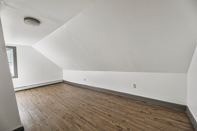 additional living space with lofted ceiling, dark hardwood / wood-style floors, and a baseboard heating unit