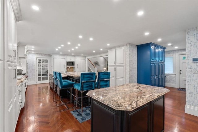 1 Croftdale, Newton, MA 02459 - kitchen featuring a kitchen island with sink, stainless steel microwave, light stone countertops, recessed lighting, and white cabinets