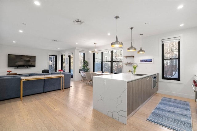 kitchen with visible vents, light wood-style flooring, modern cabinets, open floor plan, and a sink