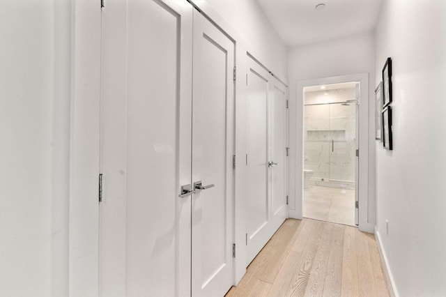 corridor featuring light wood-style flooring and baseboards