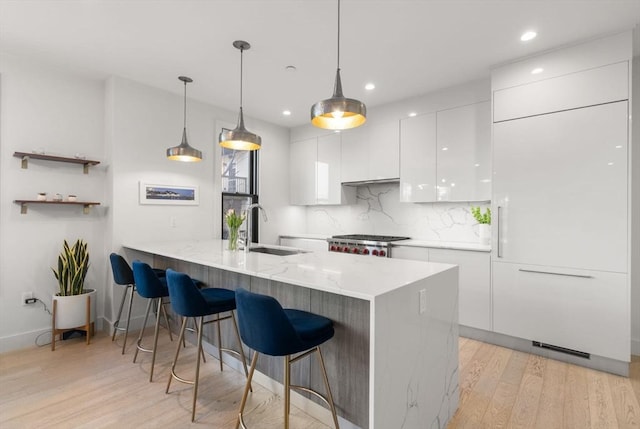 kitchen with modern cabinets, a sink, white cabinetry, and decorative light fixtures