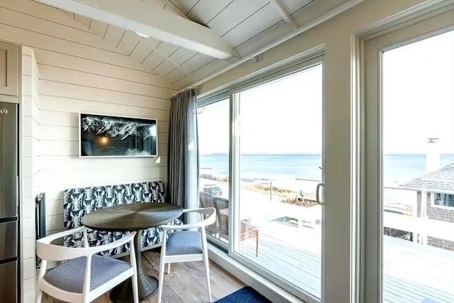 sunroom / solarium featuring lofted ceiling with beams, wood ceiling, and a water view