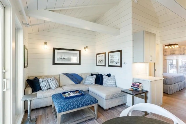 living room with high vaulted ceiling, wood walls, wood-type flooring, and beamed ceiling