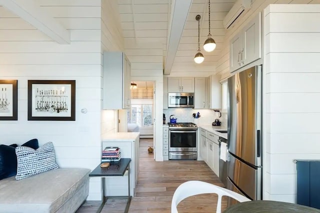 kitchen featuring stainless steel appliances, beamed ceiling, pendant lighting, a wall unit AC, and dark wood-type flooring