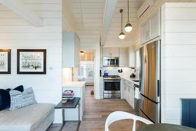 495 Commercial St Unit 9, Provincetown, MA 02657 - kitchen featuring appliances with stainless steel finishes, beam ceiling, an AC wall unit, wood finished floors, and light countertops