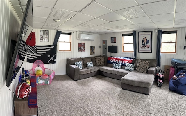 living room featuring a wall mounted AC, a drop ceiling, and a healthy amount of sunlight