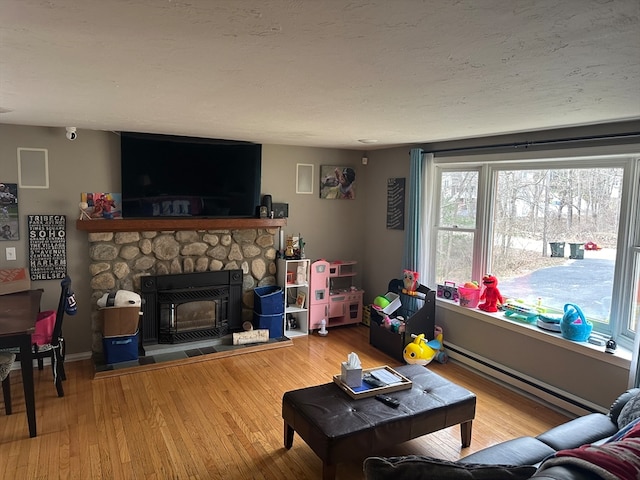 living room featuring hardwood / wood-style flooring, a stone fireplace, and baseboard heating