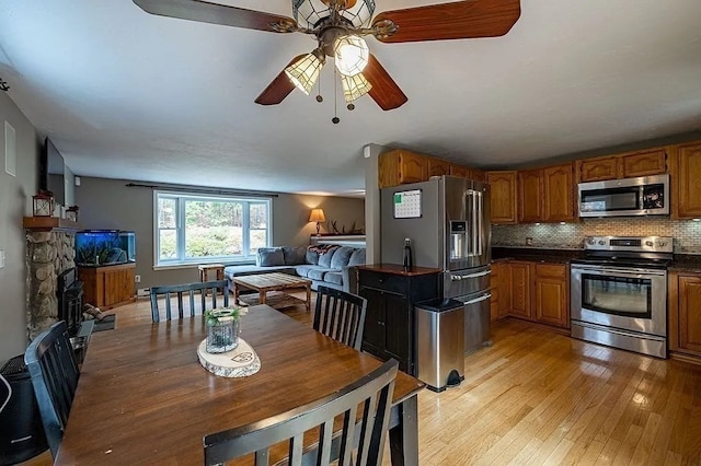 dining space featuring ceiling fan, a fireplace, and light hardwood / wood-style floors