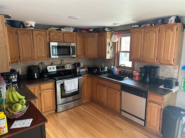 kitchen with tasteful backsplash, sink, stainless steel appliances, and light hardwood / wood-style floors