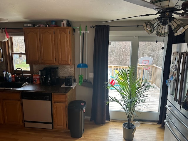 kitchen with dishwasher, sink, light hardwood / wood-style flooring, decorative backsplash, and stainless steel refrigerator