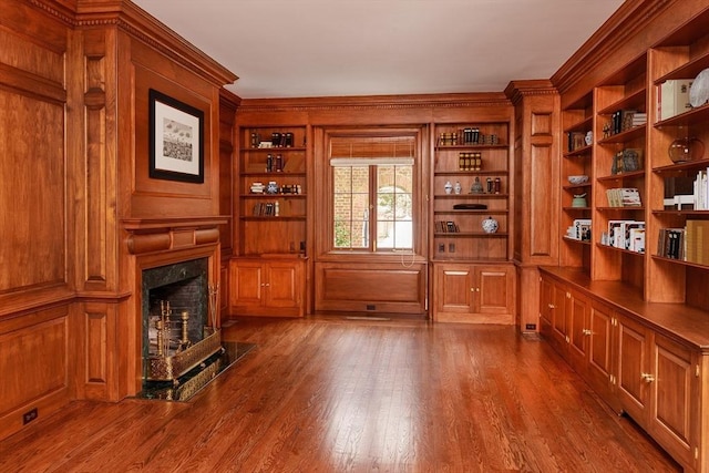 interior space featuring crown molding, built in features, dark wood-style floors, and a premium fireplace