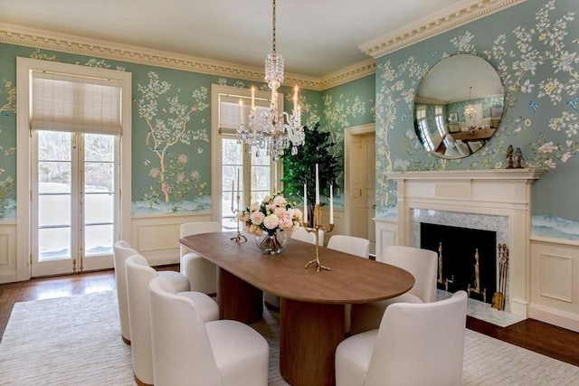 dining space with a premium fireplace, wainscoting, wallpapered walls, and wood finished floors