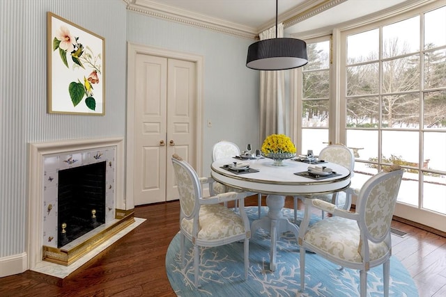 dining room featuring dark wood-type flooring, a fireplace, and crown molding