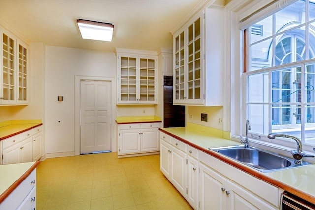 kitchen featuring glass insert cabinets, light floors, light countertops, and a sink