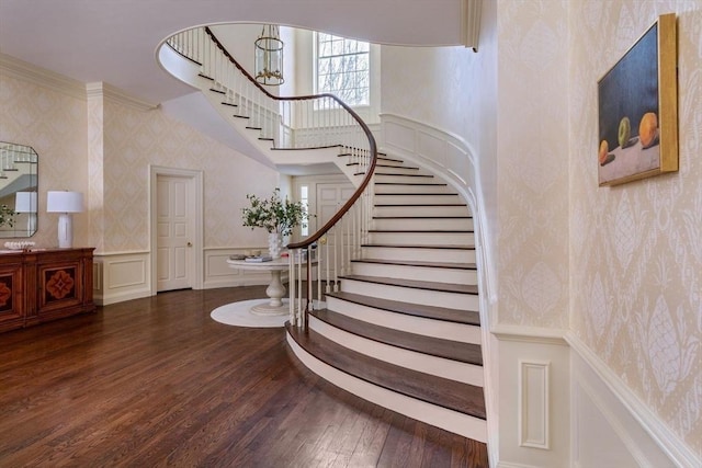 stairs with a wainscoted wall, a decorative wall, wood finished floors, and wallpapered walls