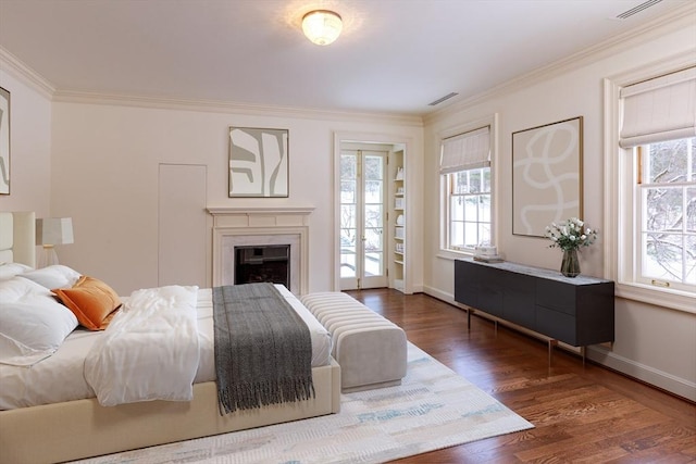 bedroom with visible vents, crown molding, baseboards, and wood finished floors