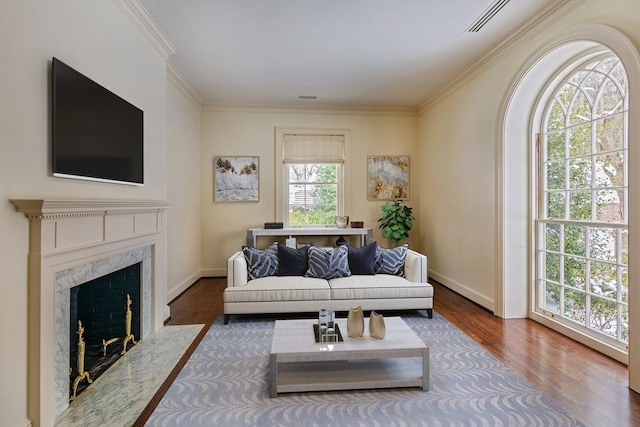 living area with a fireplace, wood finished floors, baseboards, and ornamental molding